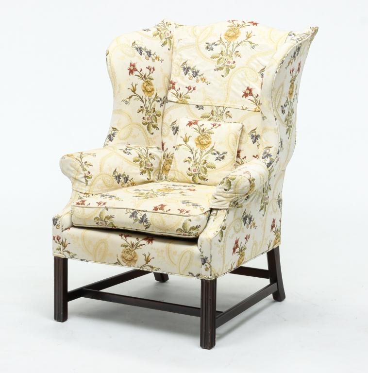 AMERICAN CHIPPENDALE STYLE WING BACK CHAIR.: Second half 20th century, mahogany. Floral patterned upholstery on an ivory background, square legs and box stretchers. Some finish wear. Comes with an extra set of arm covers and antimacasser. 19" se
