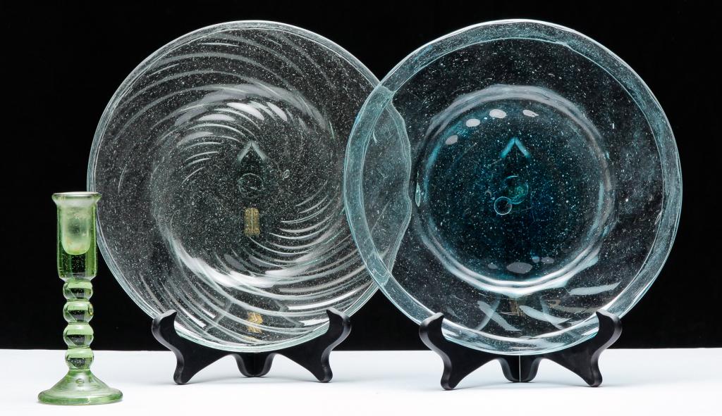 TWO BLOWN GLASS PLATES AND A CANDLESTICK.: Probably Mexican, 20th century. Two swirl rim plates with folded rims. Pale blue, 11"d. and faint green, 10.75"d. Together with a green candlestick, 6.75"h.