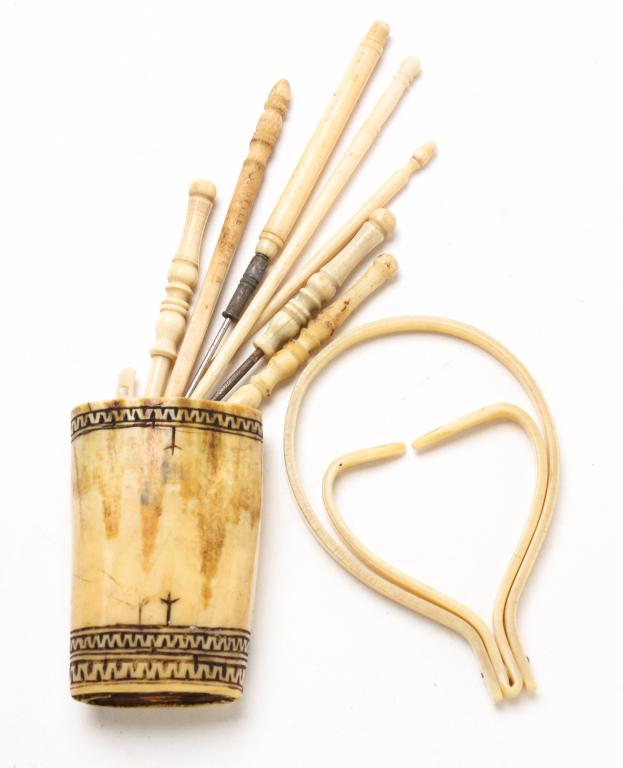 SCRIMSHAW CUP AND NEEDLEWORK HOOKS.: American and/or European, 19th-early 20th century, Small tusk cup with incised designs and wooden bottom. 2.75"h. And two bone awls and five bone lace and crochet hooks. Together with a small celluloi