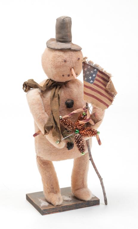 ARNETT’S COUNTRY STORE FOLK ART SNOWMAN.: American, 20th century. A stuffed snowman holding decorations and an American flag on wooden base. 22"h.