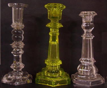 THREE GLASS CANDLESTICKS. Canary with he: THREE GLASS CANDLESTICKS. Canary with hexagonal base and paneled column and socket. Damage. 9 3/4"h. And two clear. One is Sandwich with a pressed hexagonal base and a hollow blown socket with two