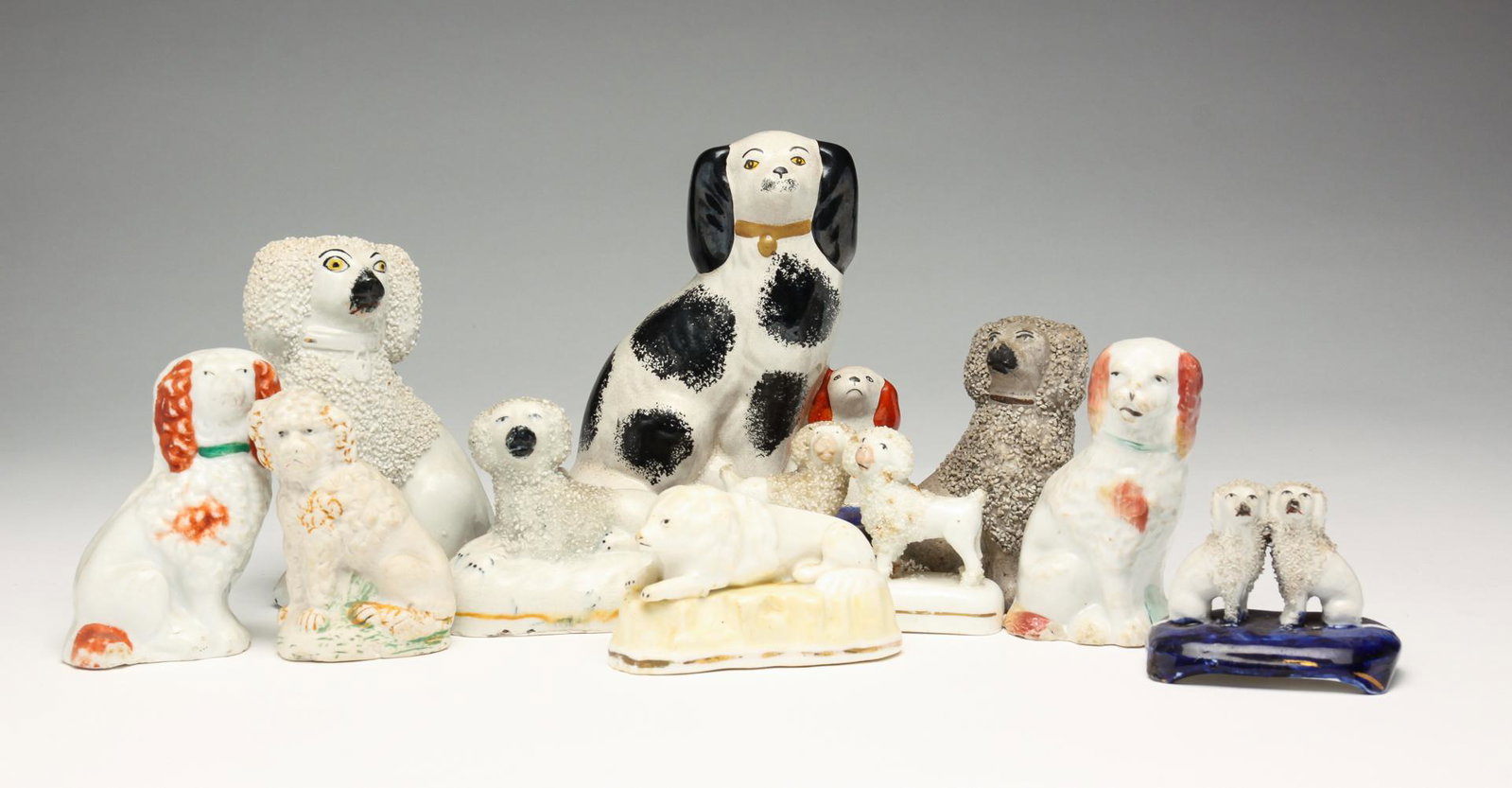 GROUP OF ELEVEN STAFFORDSHIRE DOGS.: England, mid 19th century. Eleven dogs in various poses. Some with sanded coats. Ranging in size from 5.75" - 2"h. Varying wear loss and repairs.