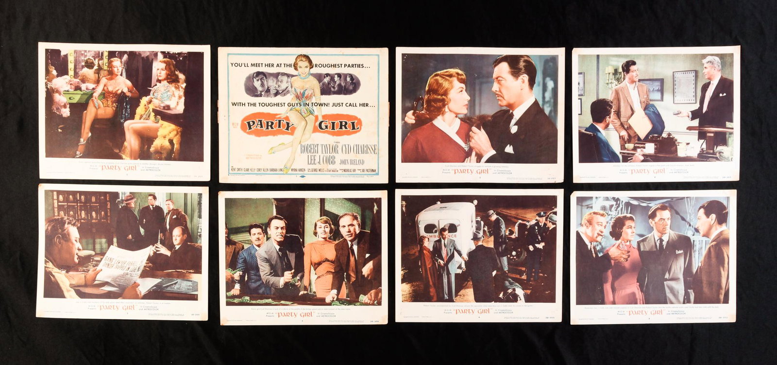 SET OF EIGHT PARTY GIRL LOBBY CARDS.: MGM, 1958. Stains including tape residue, small holes and a few small tears. 11"h. 14"w.