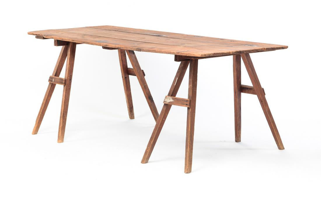 AMERICAN SAWHORSE TABLE.: Circa 1900, pine. Three board top with battens and two small sawhorses. Wear and loss. 30"h. 30"w. 72"d.