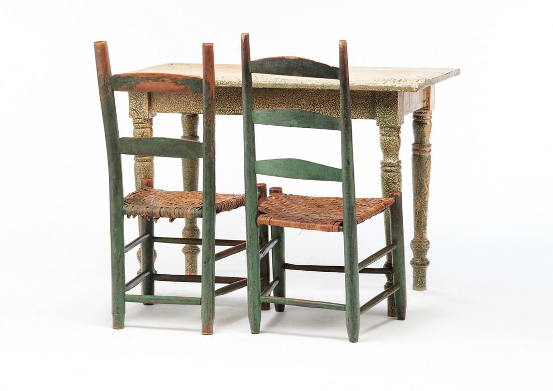 AMERICAN TABLE AND TWO CHAIRS.: Mid 19th century. The table has boldly turned legs and has worn tan paint over earlier green. Age splits and wear. 30"h. 42"w. 24.25"d. And two similar ladder back chairs with splint seats. Worn green