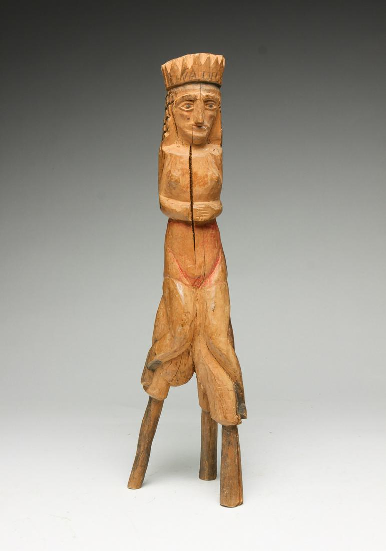 FOLK ART CARVED FIGURE OF A QUEEN.: First half 20th century. Carved branch with tripod base. Seated crowned figure with traces of pigment and scratch carved and penciled labels "Reina del Cafe", "RDO DE PMM" (?). Age splits, 15.25"h.