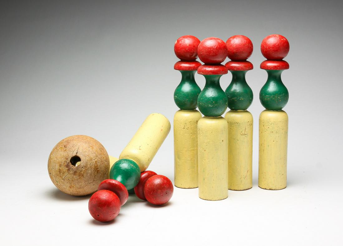 SIX AMERICAN GAME PINS.: Mid 20th century. Wooden pins with old green, red and yellow paint. Wear and age splits. 11.5"h. Together with a mismatched ball.