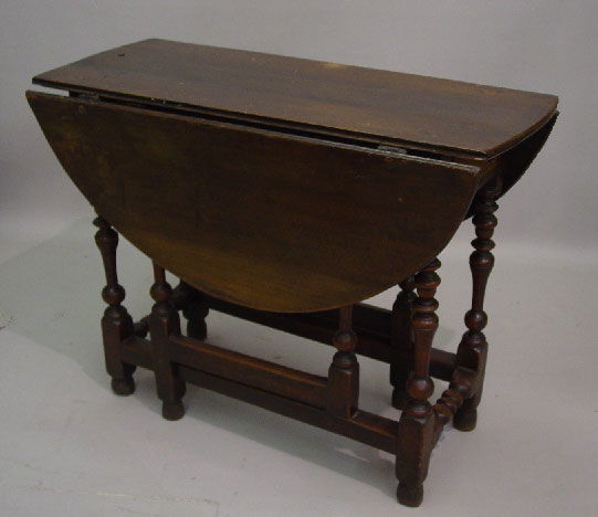 ENGLISH GATE LEG TABLE. Walnut with an o: ENGLISH GATE LEG TABLE. Walnut with an old finish. Turned feet and finely turned legs with a stretcher base. Dovetailed drawer in the apron of one end. Top, "D" shaped leaves, and drawer are old repla