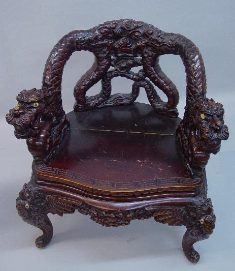 CHINESE CARVED WOODEN ARMCHAIR. Old redd: CHINESE CARVED WOODEN ARMCHAIR. Old reddish brown finish. Relief bats on the knees with scrolled feet and aprons. Incised Greek key designs on the front of the chair. Openwork dragon back with dragon