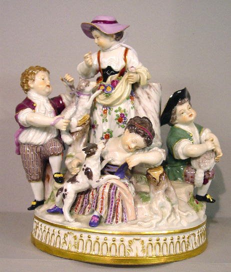 MEISSEN FIGURE GROUP. Five children at p: MEISSEN FIGURE GROUP. Five children at play with a dog and two lambs. Hand painted polychrome enamel with gilt trim. Underglaze blue crossed swords mark on the base. Minor edge damage and a few minor
