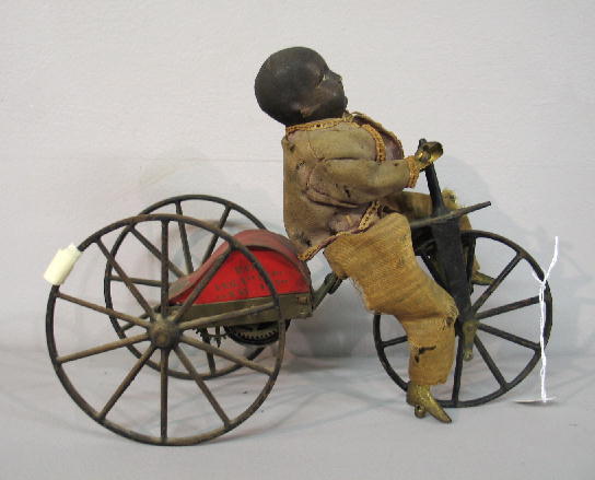 EARLY WIND UP TOY. Stevens & Brown toy with a youn: EARLY WIND UP TOY. Stevens & Brown toy with a young African American boy on a tricycle. Formed cloth body and head with original paint and worn original clothing. Articulated brass limbs. Cast iron an