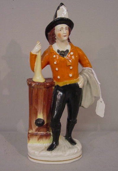 STAFFORDSHIRE FIGURE OF A FIREMAN. Unusual figure: STAFFORDSHIRE FIGURE OF A FIREMAN. Unusual figure showing a fireman in uniform leaning against a water pump with his horn. Hand painted with a gilt trim around the badge on his hat. 9 1/4"h.