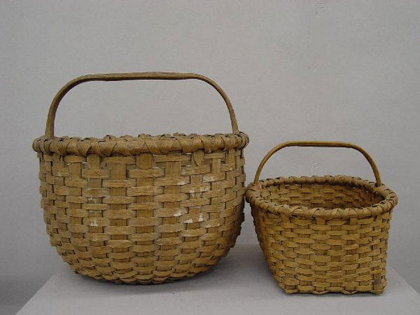 TWO WOVEN SPLINT GATHERING BASKETS. Both have a na: TWO WOVEN SPLINT GATHERING BASKETS. Both have a natural dry finish. Pictured is a large round example. 15"d. 14 1/4"h. Other is oblong with an arched handle and coarsely woven bottom. A few broken spl