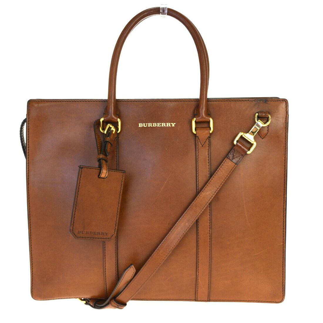 Authentic BURBERRY TOTE Leather Hand Bag: Brand: BURBERRY Material: Leather Style: Hand bag Color: Brown Size(inch): W 14.6 x H 11.8 x D 3.5 "(approx.) Country of Origin: Romania Come with: Shoulder strap,Name tag All Bidhaus items come with