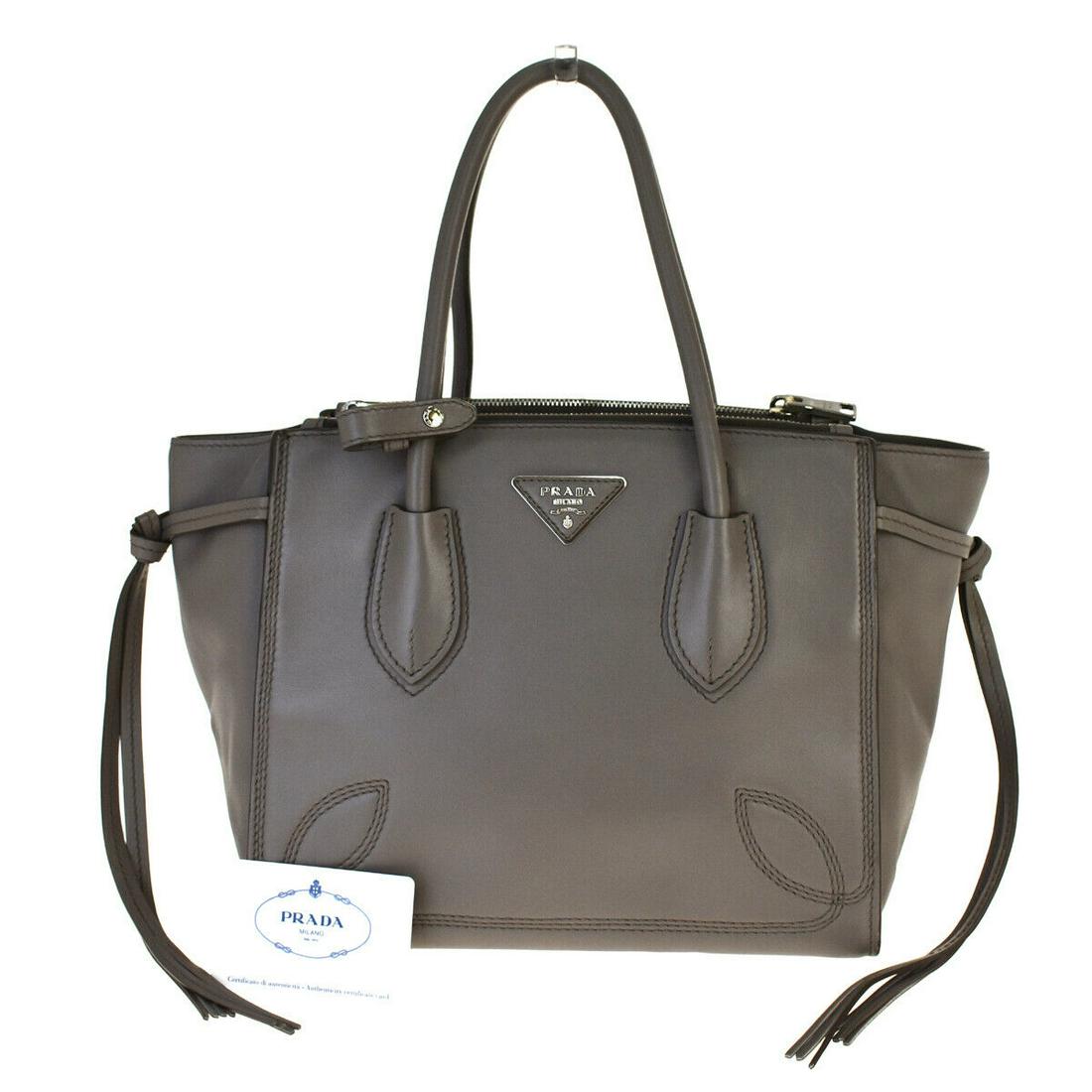 Authentic PRADA Leather Hand bag: Brand: PRADA Material: Leather Style: Hand bag Color: Gray Size(inch): W 10.2 x H 8.7 x D 6.7 "(approx.) Country of Origin: Italy Come with: Authenticity Card,Handle holder All Bidhaus items come with