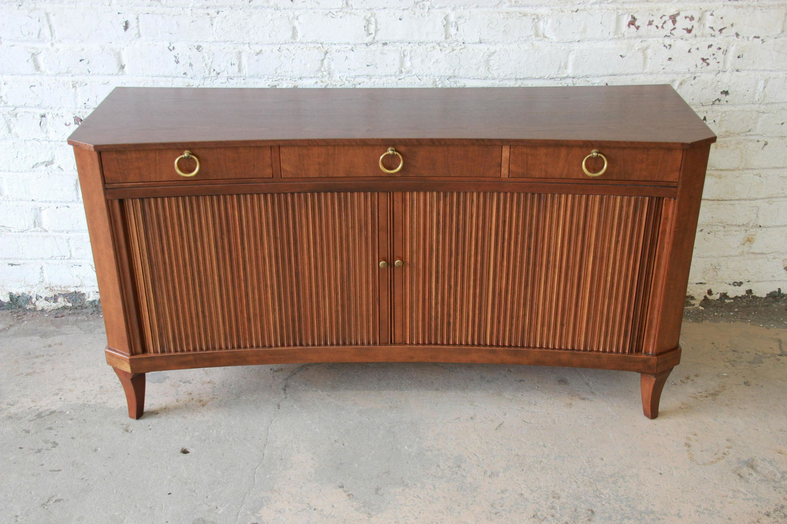 Authentic Michael Taylor for Baker Furniture Regency: Offering an exceptional mid-century Regency style curved front tambour door sideboard or credenza by Baker Furniture. The credenza is made from solid fruitwood and features a curved front with canted