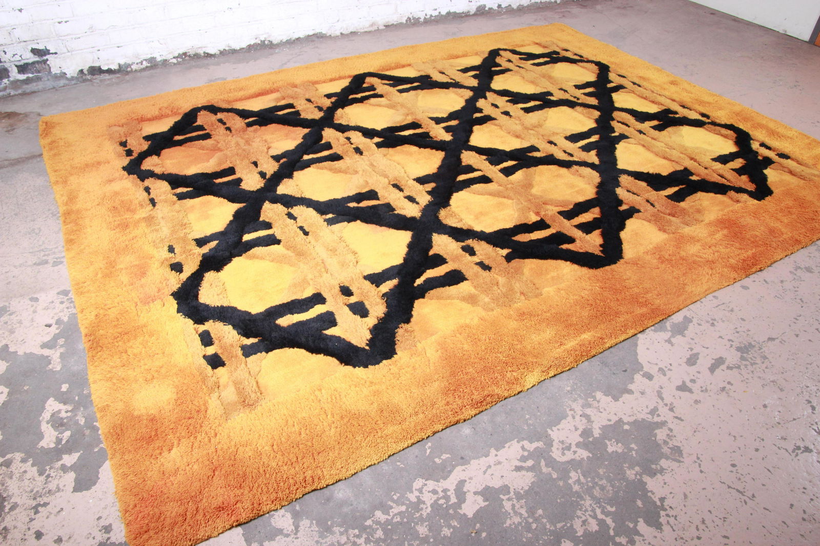 Edward Fields Abstract Sculpted Shag Rug 1974: A unique and exceptional sculpted shag rug made by Edward Fields in 1974. The rug has a very thick and plush wool pile with an orange field and black geometric design. The original label is present. P