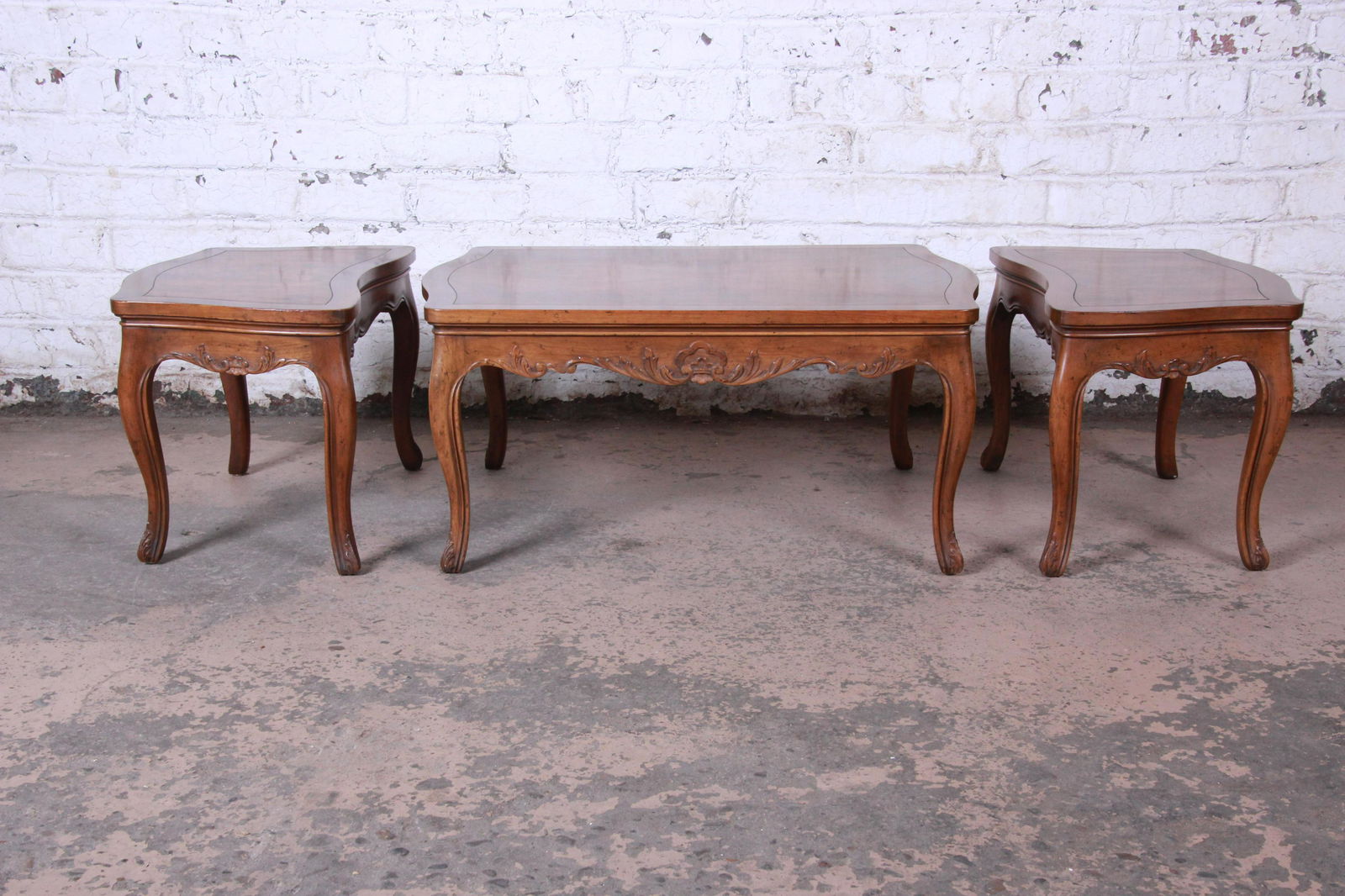 Baker Furniture French Carved Burl Wood Coffee Table: Offering a gorgeous French carved burl wood three-piece coffee and end tables set by Baker Furniture. The tables features stunning burled wood grain and nice French carved details. The side tables uni