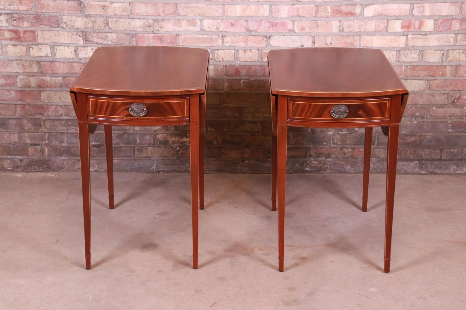 Baker Furniture Inlaid Mahogany Pembroke Tea Tables: A gorgeous pair of Sheraton style Pembroke nightstands or end tables By Baker Furniture USA Circa 1940s Mahogany with satinwood string inlay and original brass hardware. Measures: 19.13"W x 29.25"D x