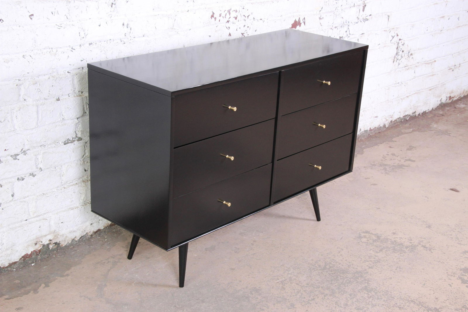 Paul McCobb Black Lacquered Planner Group Six-Drawer: An excellent six drawer black lacquered Planner Group dresser by Paul McCobb. The dresser sits upon splayed legs and offers six smooth sliding drawers with iconic brass pulls from this McCobb line. Th