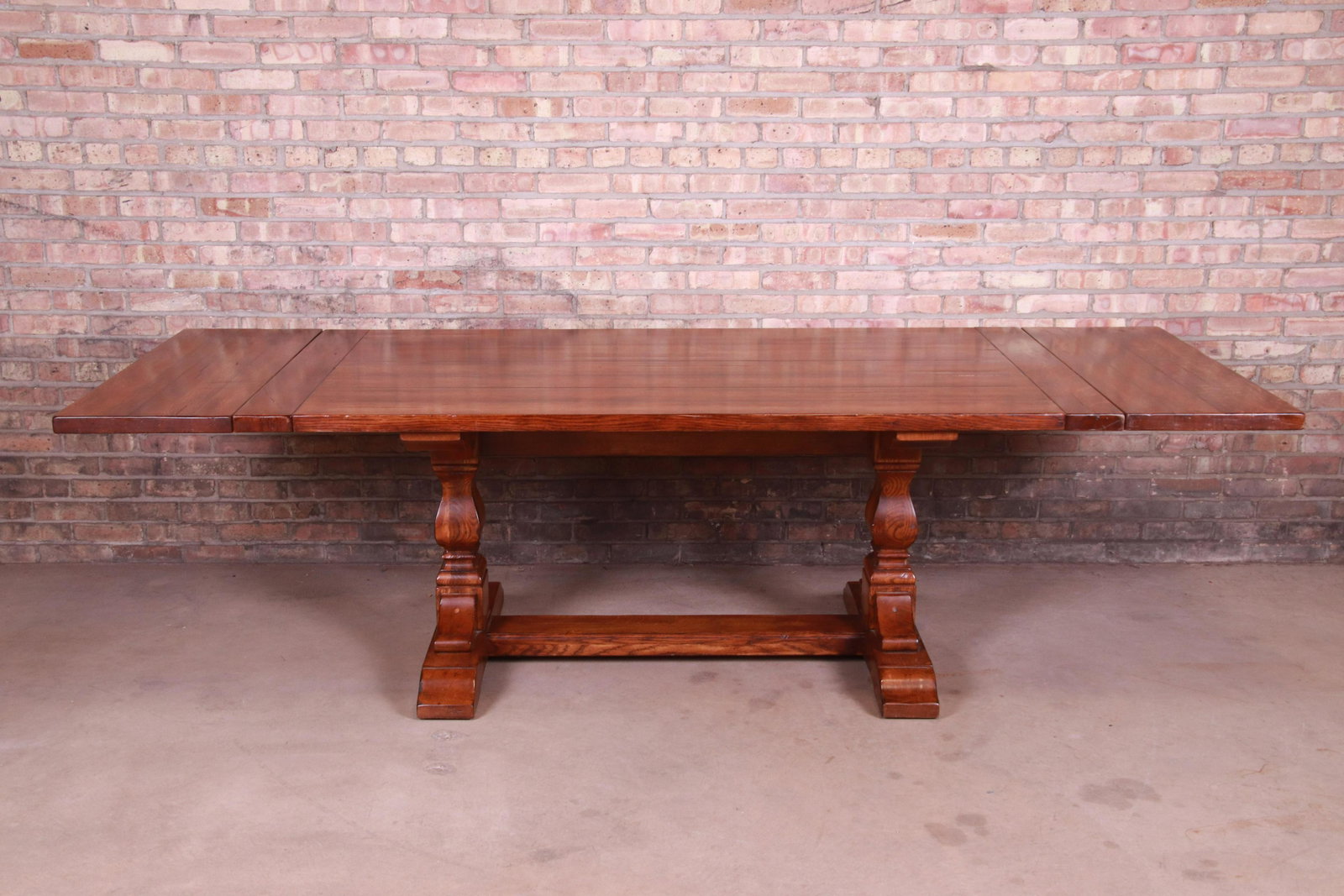 Stickley Arts & Crafts Solid Oak Trestle Base Harvest: An exceptional Arts & Crafts style solid oak trestle base extension dining table By Stickley Furniture USA Late 20th Century Measures: 76"W x 42"D x 30"H. Extends up to 105.75"W with two 14.88" le