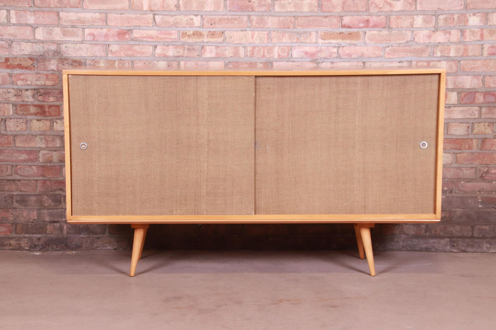 Paul McCobb Planner Group Mid-Century Modern Maple: An exceptional minimalist mid-century modern sliding door sideboard or credenza By Paul McCobb for Winchendon Furniture "Planner Group" USA 1950s Solid maple with sliding grasscloth doors. Measures: 6