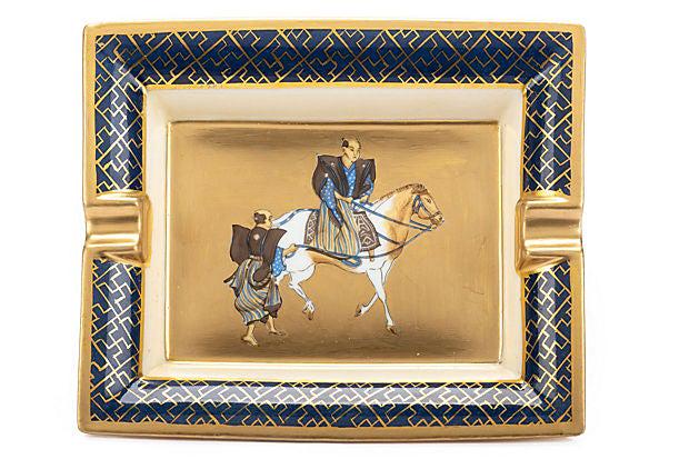 Hermes Samurai Gold Porcelaine Ashtray: Hermes Samurai Gold Porcelaine Ashtray Condition: Very Good; minor wear on rear suede Era: Contemporary; 2000s Dimensions: 8" L x 6" W x 2" H Materials: porcelain suede Color: gold blue Hermes signatu