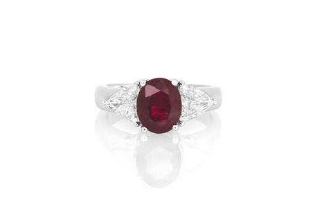 2.52 Oval Shaped Ruby & Diamond Ring: 2.52 Oval Shaped Ruby & Diamond Ring Estate ring finely crafted in 18K white gold. It features a vibrant red 2.52 carat oval shaped ruby flanked by trillion cut diamonds weighing a total of 1.05