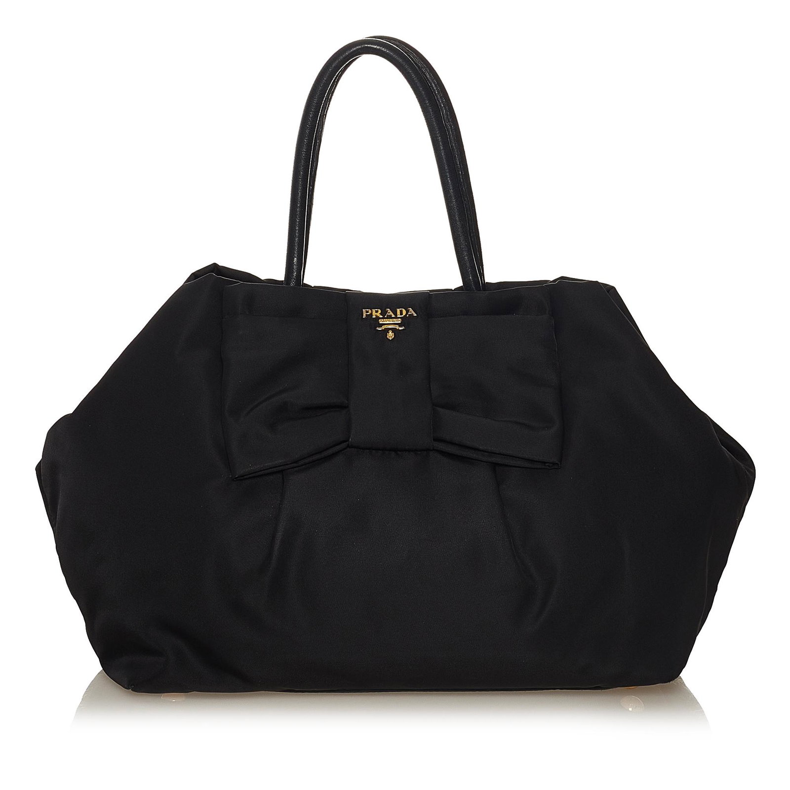 Prada Fiocco Bow Tessuto Tote Bag: Prada Fiocco Bow Tessuto Tote Bag This tote bag features a nylon body with ribbon detail rolled leather handles an open top with a magnetic snap button closure and interior zip pockets. Brand: Prada M