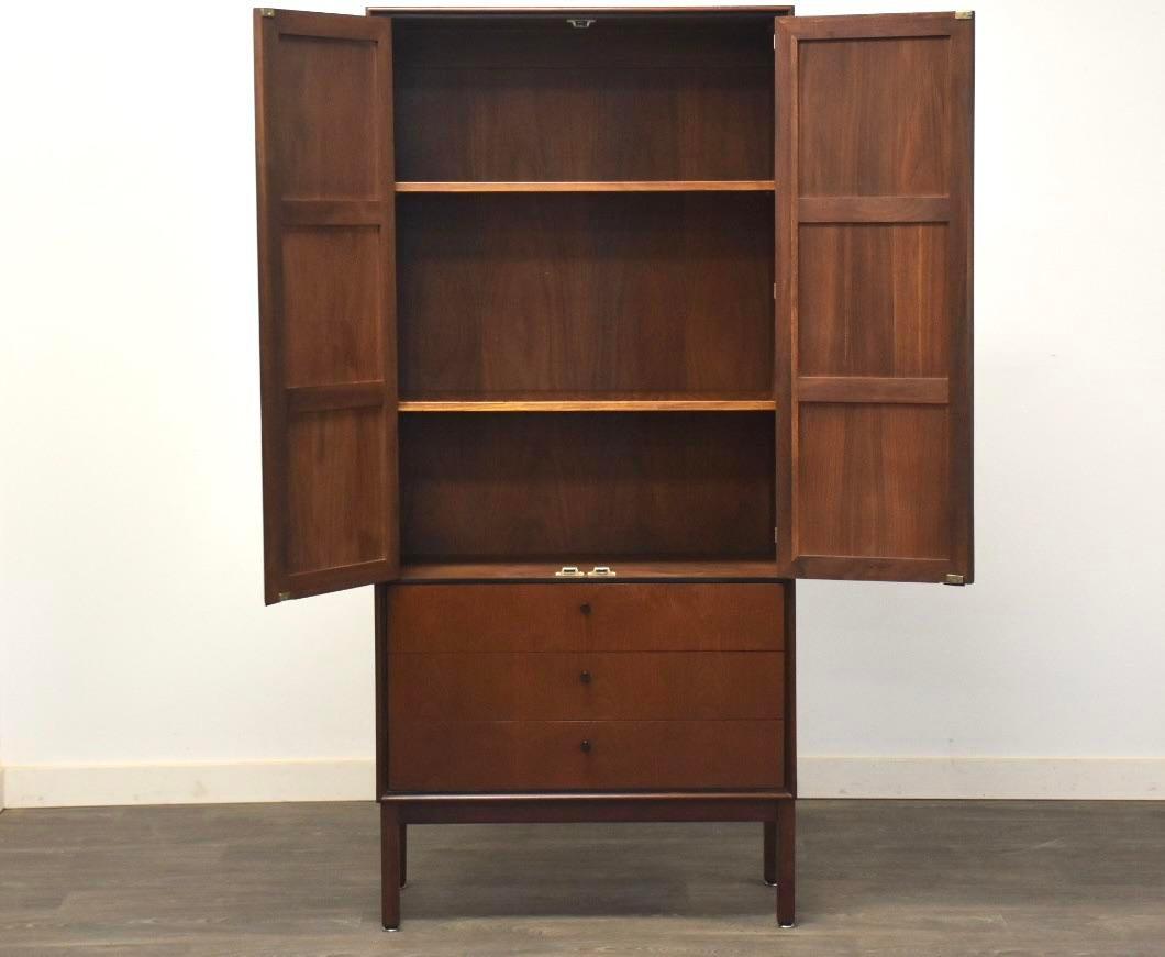 Walnut and Cane Armoire by Jack Cartwright: Walnut and Cane Armoire by Jack Cartwright A mid century modern walnut armoire with cane doors black knobs black leather finger pulls designed by Jack Cartwright for Founders. 30.25". wide 16" deep. 6