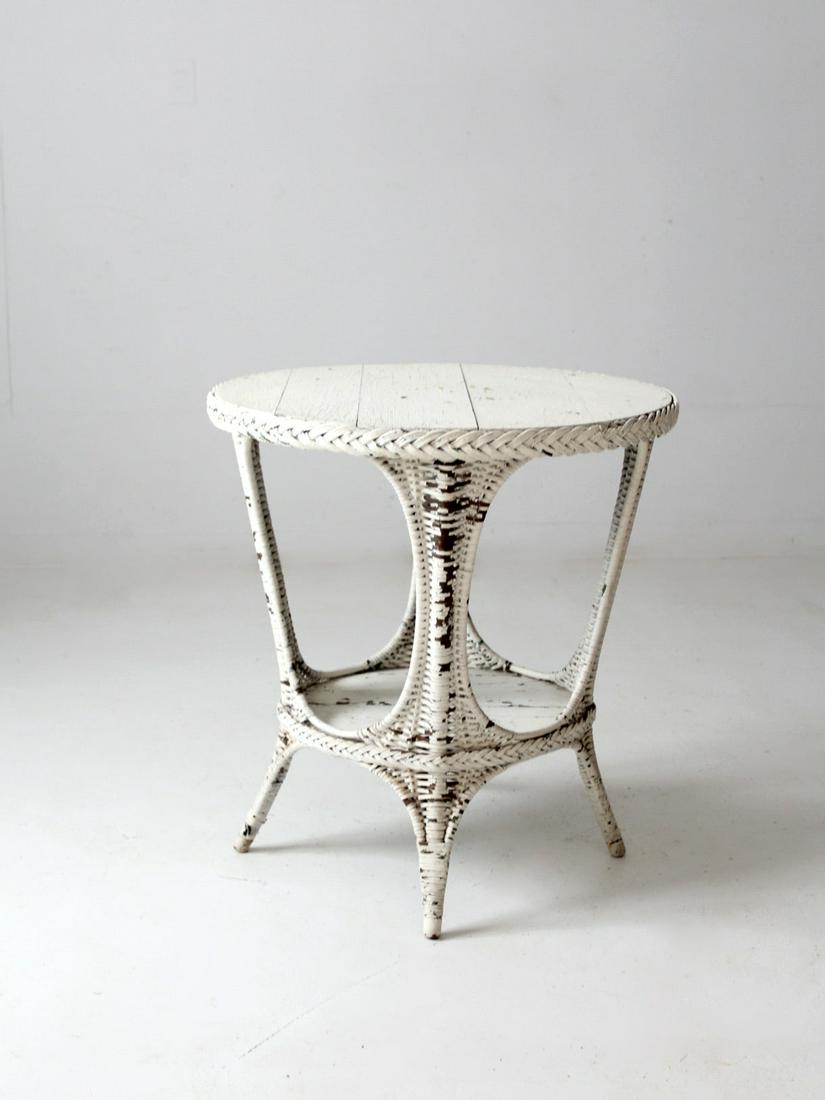 Antique White Wicker Table: Antique White Wicker Table This is an antique wicker table. The white wicker accent table features a round painted wood top and stretcher shelf. Lovely chippy paint cottage style. Height 29.75 inch 75