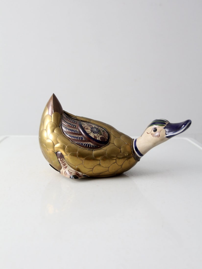 Vintage Mexican Brass & Ceramic Duck: Vintage Mexican Brass & Ceramic Duck This is vintage brass and ceramic folk art duck in the style of Sergio Bustamante. Brass "feathers" encase the painted ceramic duck. Length 12.25 inch 31.1 cm Widt