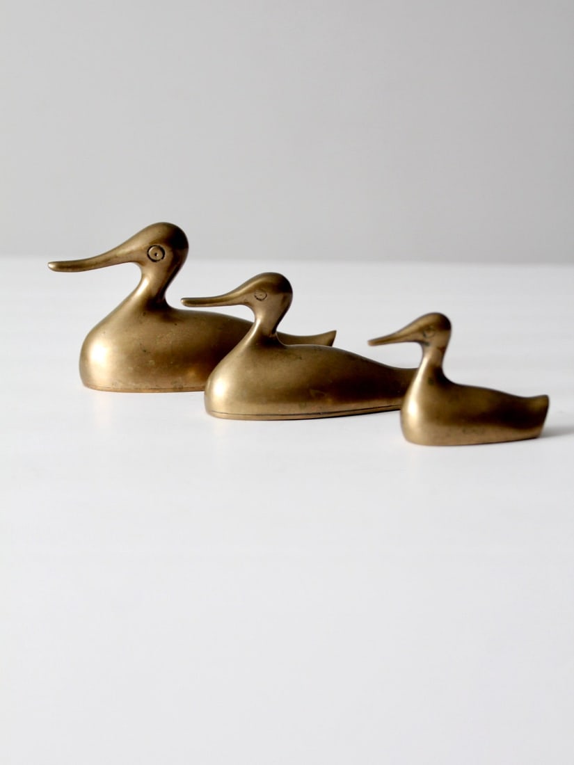 Mid-Century Brass Ducks Set: Mid-Century Brass Ducks Set Here is a set of mid century brass duck figures. The three ducks with their exaggerated bills makes this a very charming set. Place on a mantel desk or book shelf. Large 5.