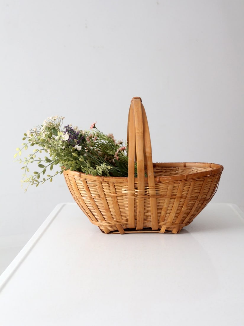Vintage Wicker Basket: Vintage Wicker Basket Add a farmhouse vintage touch to your home with this woven wicker basket! With its bentwood handle its perfect for filling with freshly-picked flowers from the garden or for tidy