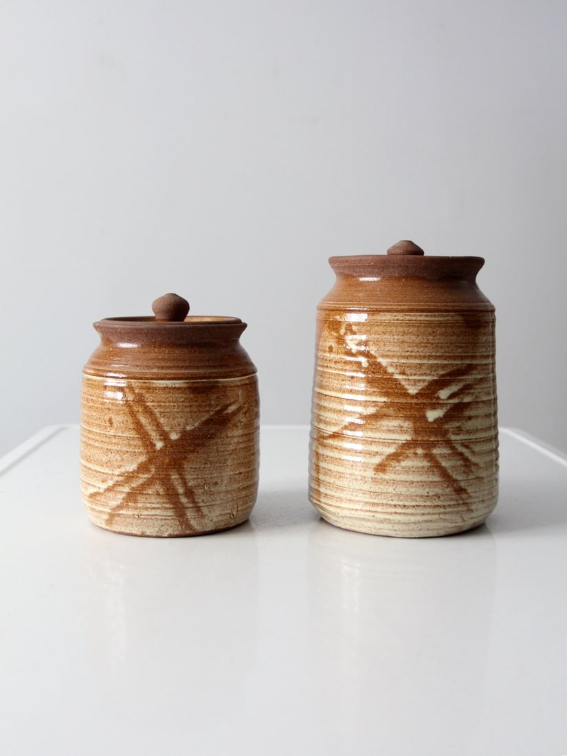 Vintage Studio Pottery Jars Set 2: Vintage Studio Pottery Jars Set 2 This is a pair of vintage studio pottery jars. Signed by the artist the hand-crafted jars feature a warm speckled brown ombre glaze with painted front design. They ha