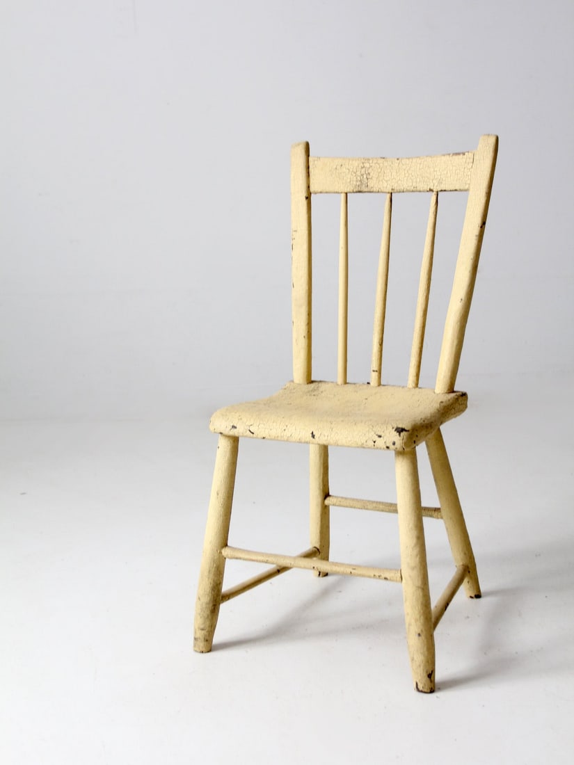 Antique Primitive Chair: Antique Primitive Chair This is an antique primitive chair. The small wooden spindle back chair features a plank seat and beautifully aged cream paint. The smaller size of the chair makes it a wonderf