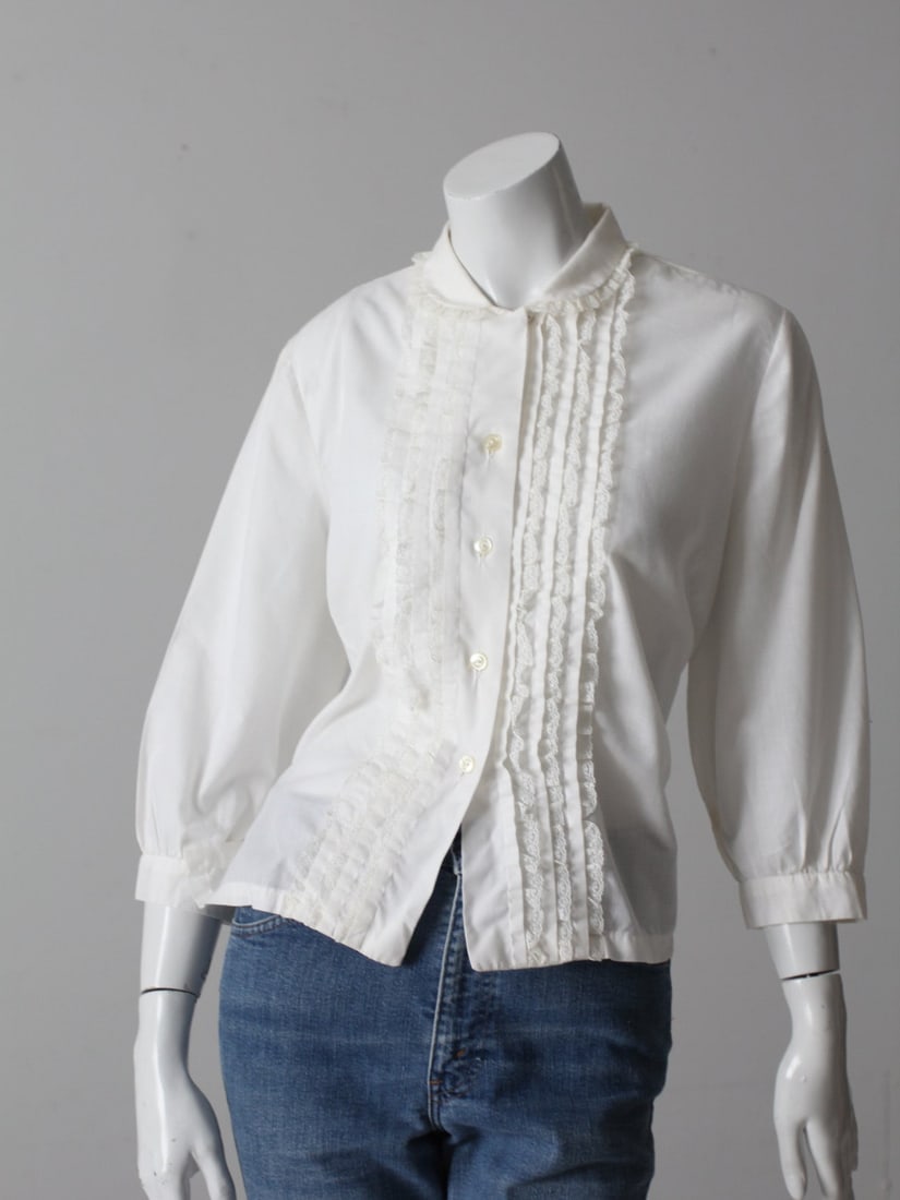1960s Vintage Judy Bond Blouse with Lace Ruffle Trim and Peter Pan Collar: 1960s Vintage Judy Bond Blouse with Lace Ruffle Trim and Peter Pan Collar This is a 1960s vintage Judy Bond blouse. The white cotton top features lace ruffle trim down the bust with a Peter Pan collar