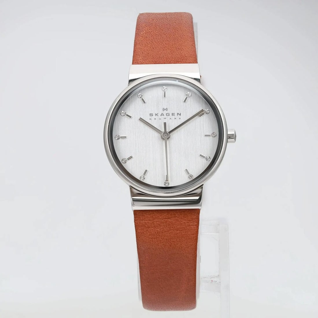 Skagen Ancher 26mm Quartz Watch Silver Dial Brown Leather Strap: Skagen Ancher 26mm Quartz Watch Silver Dial Brown Leather Strap The Skagen Ancher is a stylish and casual wristwatch designed for women. This timepiece features a sleek silver dial with non-numeric ho