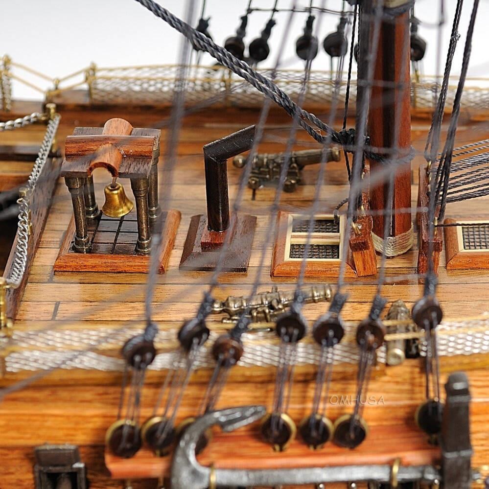 HMS Victory Replica in Mahogany Display Case: HMS Victory Replica in Mahogany Display Case Showcasing a stunning replica of the HMS Victory, this meticulously handmade model is displayed within a dark mahogany case. The model features intricate d