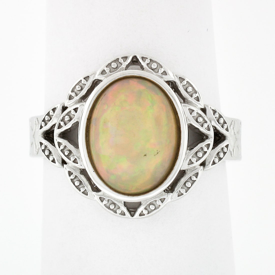 Vintage Sterling Silver Opal Solitaire Ring with Textured Band: Vintage Sterling Silver Opal Solitaire Ring with Textured Band This exquisite vintage ring features a stunning oval cabochon Ethiopian opal set in solid sterling silver. The intricate open textured wo