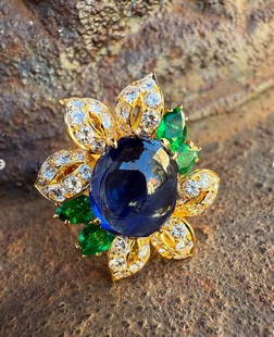 Exquisite 18k Yellow Gold GIA Certified Sapphire Emerald Diamond Ring: Exquisite 18k Yellow Gold GIA Certified Sapphire Emerald Diamond Ring This exquisite 18k Yellow Gold cocktail ring features a stunning floral design, showcasing a captivating 5.22ct royal blue cabocho