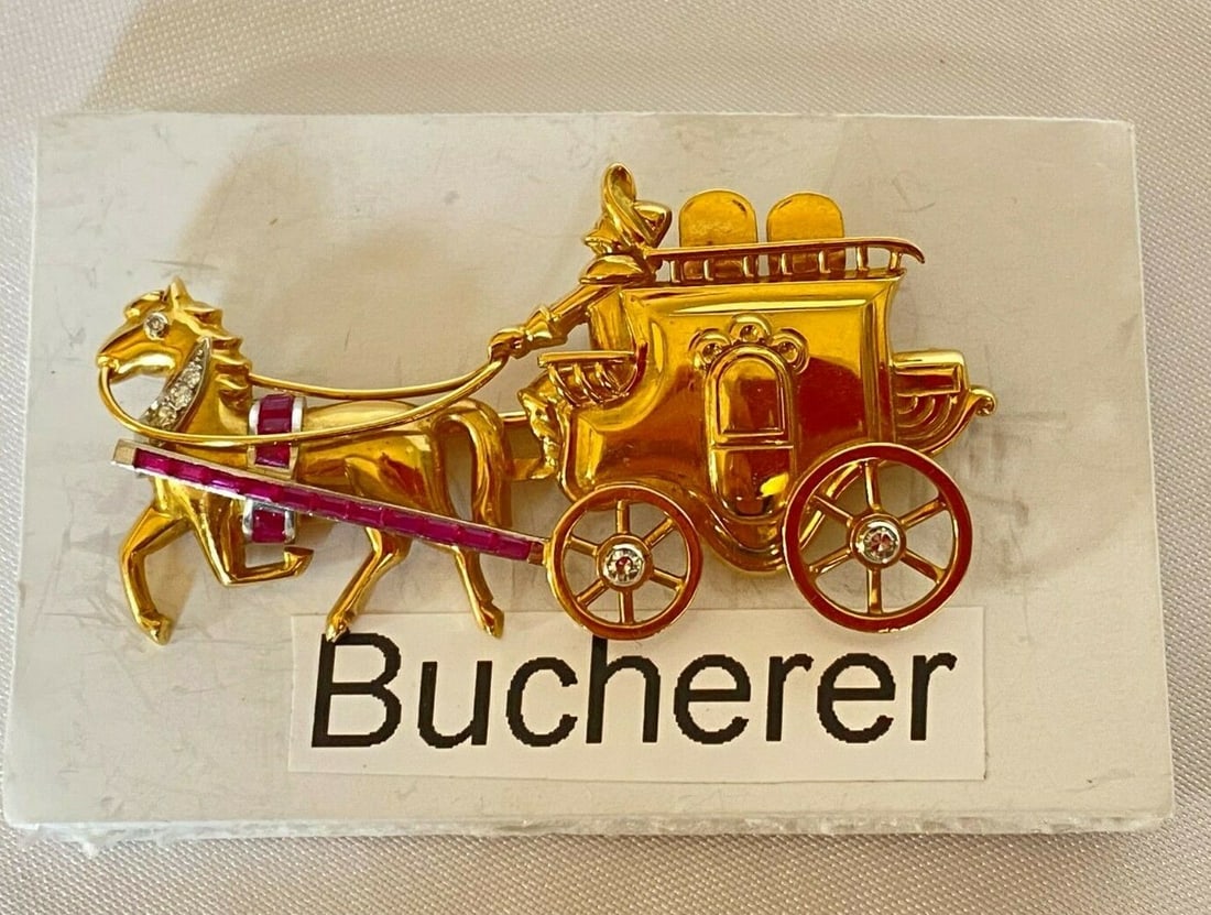 Bucherer Swiss 18K Gold Diamond Ruby Carriage Brooch: Bucherer Swiss 18K Gold Diamond Ruby Carriage Brooch This exquisite brooch, crafted by Swiss goldsmith Bucherer, showcases a stunning combination of 18K yellow gold, diamonds, and rubies. The brooch f