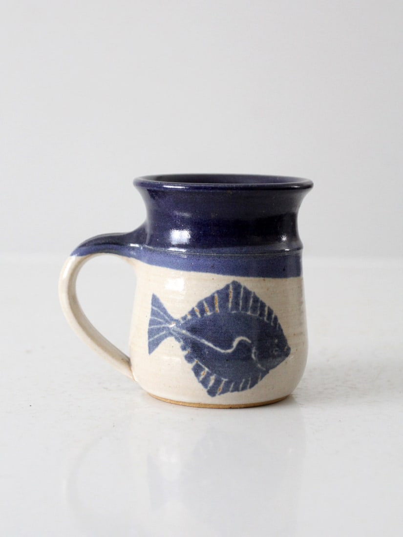 Vintage Jeanne Stolberg Pottery Mug Blue Cream Fish Design: Vintage Jeanne Stolberg Pottery Mug Blue Cream Fish Design This vintage studio pottery mug, crafted by Alaskan artist Jeanne Stolberg, showcases a stunning blue and cream glaze adorned with a unique h