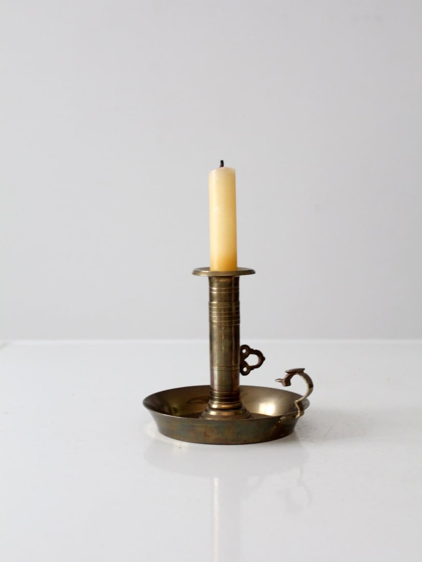 Vintage Antique Brass Chamberstick with Pushup Lever: Vintage Antique Brass Chamberstick with Pushup Lever This antique brass chamberstick is a charming piece featuring a taper candlestick holder with a pushup lever and a ring hold. Its condition reflect