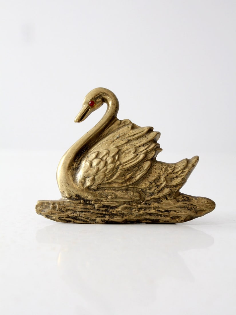 Vintage Brass Swan Paperweight with Red Glass Eye Accent: Vintage Brass Swan Paperweight with Red Glass Eye Accent This vintage brass swan figure serves as a charming decorative piece or practical paperweight. The intricately designed brass plaque depicts a