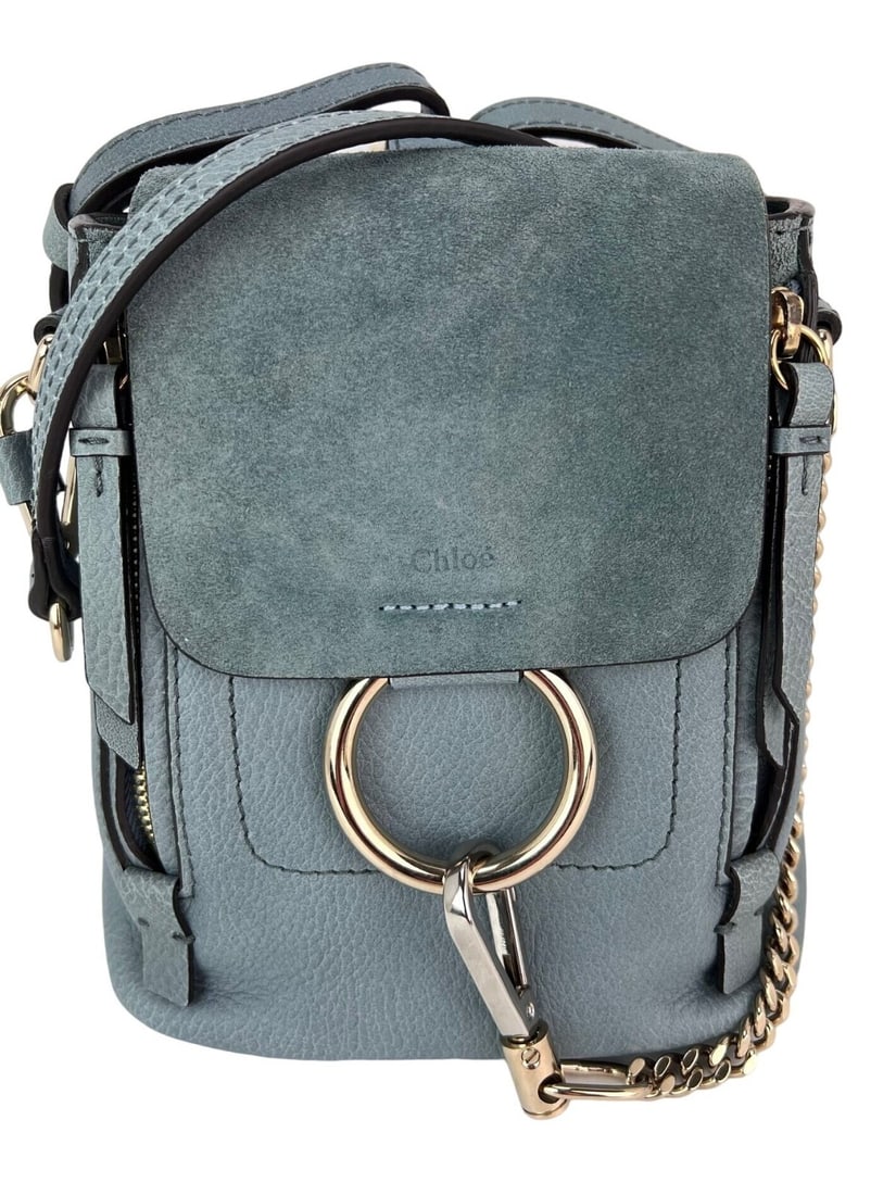 Chloe Faye Mini Blue Suede Leather Backpack with Dust Bag: Chloe Faye Mini Blue Suede Leather Backpack with Dust Bag Introducing the Chloe Blue Faye Mini Backpack, a stylish and functional accessory crafted from premium leather suede. This mini backpack featu