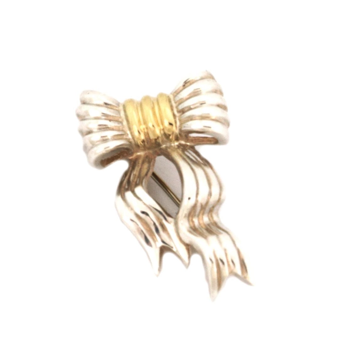 Tiffany & Co. 925 Silver 18k Gold Grooved Ribbon Bow Brooch: Tiffany & Co. 925 Silver 18k Gold Grooved Ribbon Bow Brooch Enhance your accessory collection with this exquisite brooch from Tiffany & Co. Crafted from sterling silver, this piece features an elegant