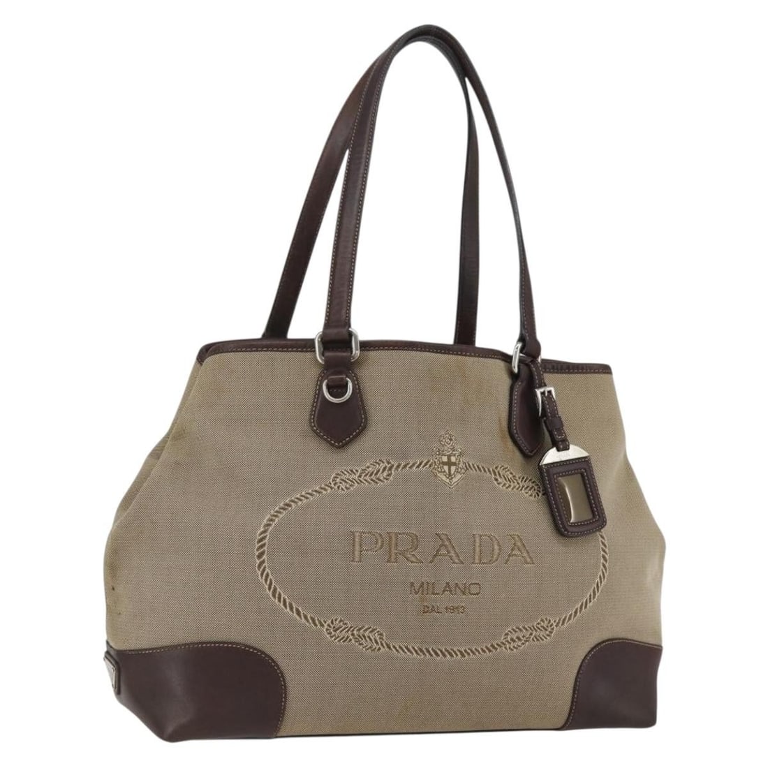 PRADA Beige Silver Canvas Tote Bag with Name Tag Auth: PRADA Beige Silver Canvas Tote Bag with Name Tag Auth This authentic PRADA Tote Bag features a stylish beige and silver color scheme, crafted from durable canvas. With dimensions of approximately 14.6
