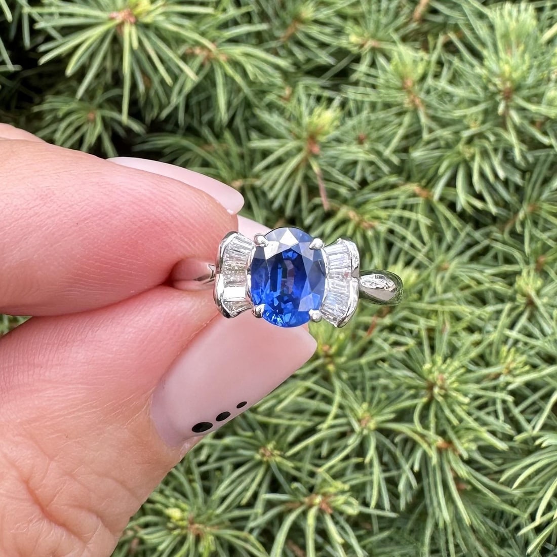 Platinum Bow Style Ring with 1.32ct Blue Oval Sapphire and Baguette Diamonds: Platinum Bow Style Ring with 1.32ct Blue Oval Sapphire and Baguette Diamonds This exquisite ring features a stunning natural oval sapphire, beautifully prong set in solid platinum. The sapphire, measu