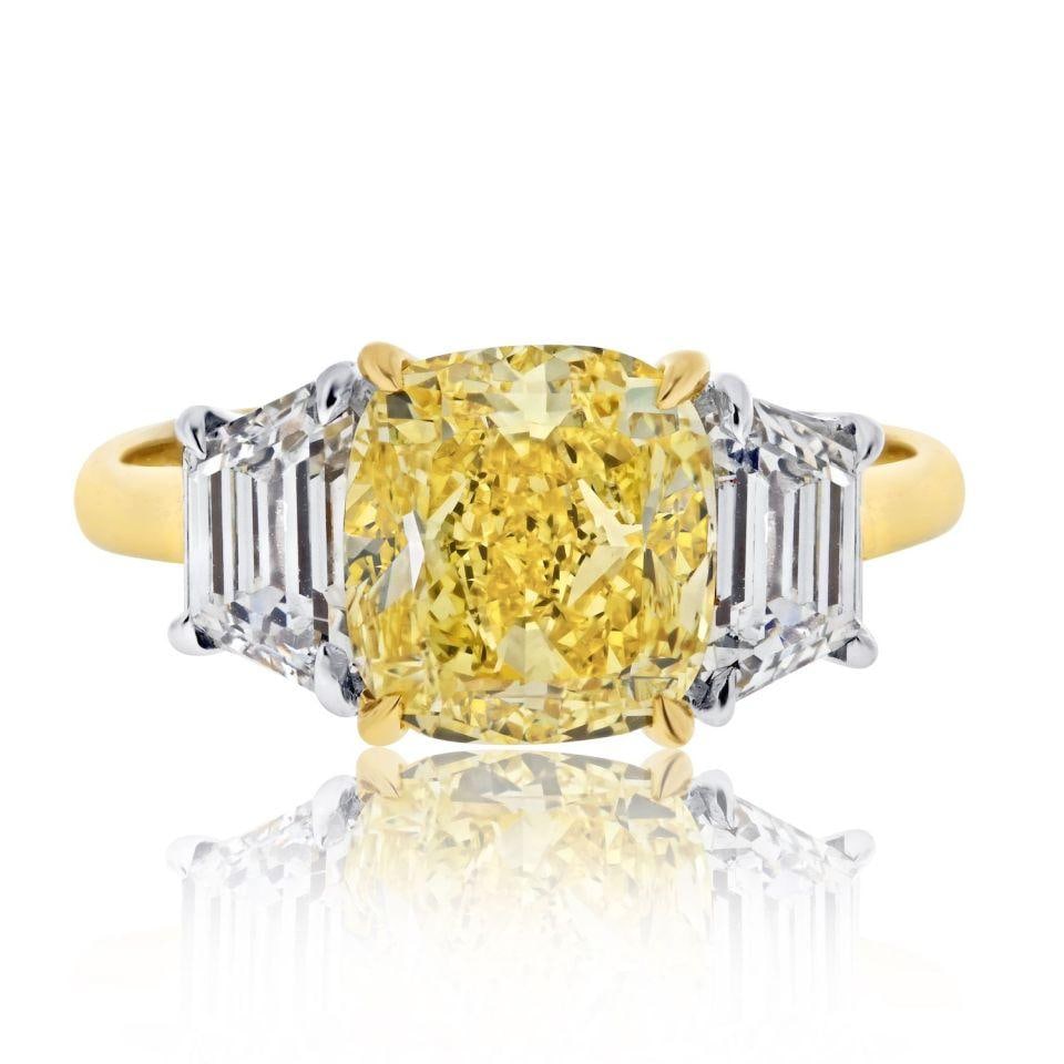 3.03ct GIA Fancy Vivid Yellow Diamond Three Stone Ring in 18K Gold: 3.03ct GIA Fancy Vivid Yellow Diamond Three Stone Ring in 18K Gold Indulge in luxury with this exquisite 18K Yellow Gold Fancy Yellow Ring featuring a stunning 3.03ct Fancy Vivid Yellow Cushion Cut di
